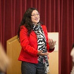 Presenter standing in front of podium smiling and speaking